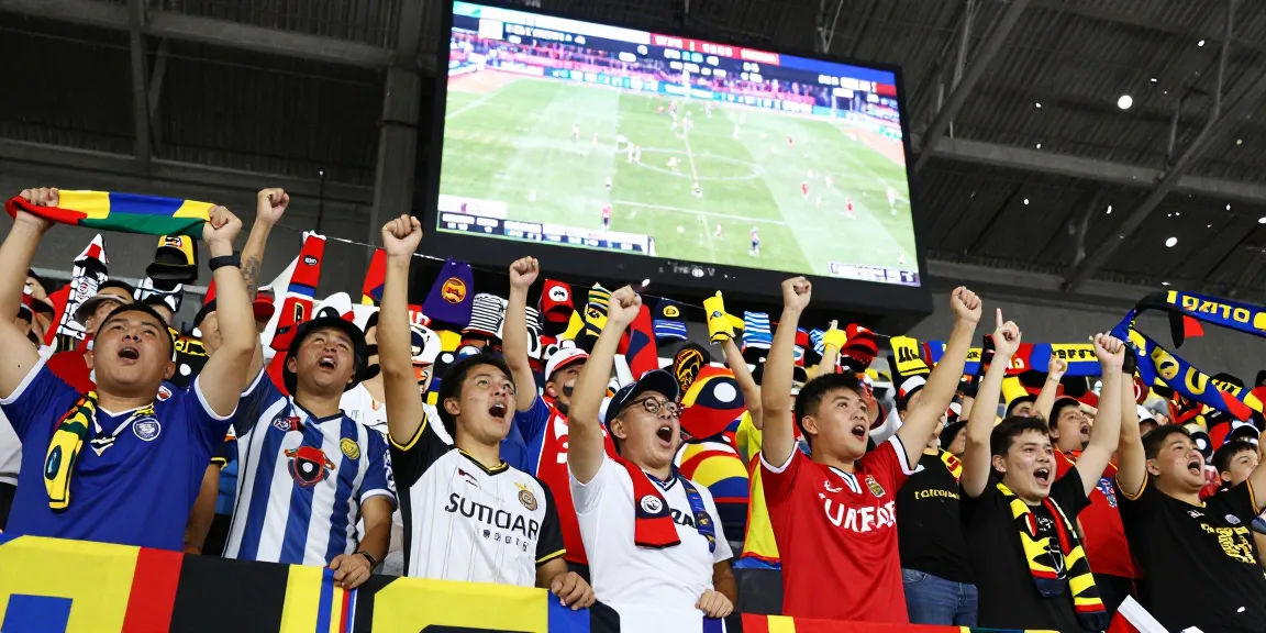 Fans at a stadium celebrating while checking Daftar Bola88 for betting odds.